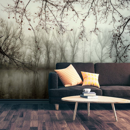 A serene living room featuring a dark gray couch with vibrant pillows, a small white coffee table with a cup, set against a Decor2Go Wallpaper Mural of Murky Forest Wallpaper Mural.