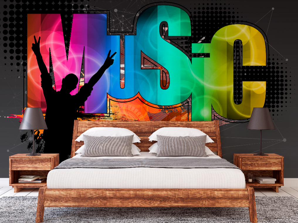 A vibrant Decor2Go Wallpaper Mural featuring the word "music" in colorful, bold letters on a feature wall in a contemporary living room with a dark couch, patterned pillows, a coffee cup on.