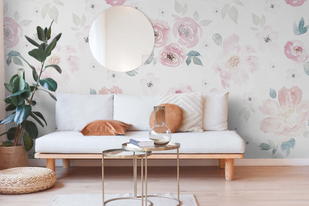 A cozy living room with a white sofa, Decor2Go Wallpaper Mural, and a round mirror. Modern gold tables hold books and a glass vase, and a potted plant adds a green touch.