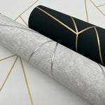 The Neutrals & Gold Metallic Cascade Wallpaper from York Wallcoverings features dramatic metallic designs in black with shimmering gold lines and light gray with silver details, laid out echoing their patterns, making these rolls standout selections from the Modern Metals Collection.