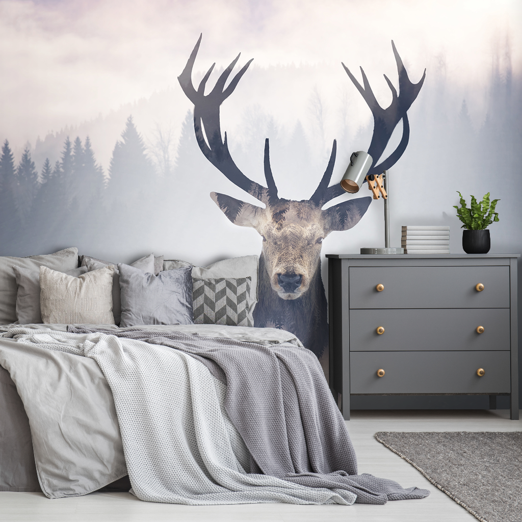 A modern bedroom featuring a large outdoor mural of an Oh Deer! with expansive antlers, set against a misty forest backdrop. The room includes a neatly made bed and a grey dresser adorned with plants from Decor2Go Wallpaper Mural.