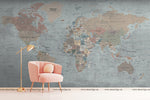 A minimalist room with a Decor2Go Wallpaper Mural Old World Map Wallpaper Mural and a single pink armchair next to a stylish gold floor lamp.