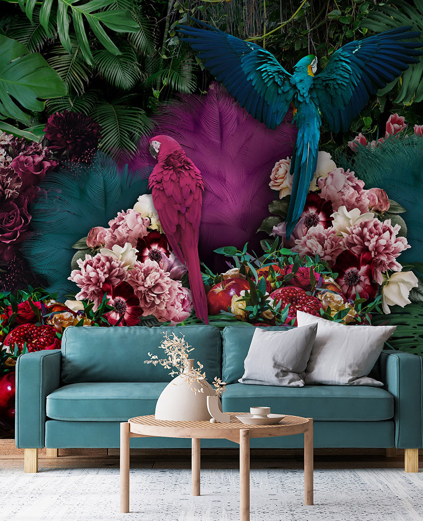A vibrant living room scene with a teal sofa against a Parrot Paradise Wallpaper Mural from Decor2Go Wallpaper Mural featuring oversized flowers and two majestic parrots, one in flight and one perched, with a small wooden coffee table in front.