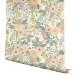 The Pastels Garden Party Wallpaper by York showcases a vibrant floral design with pink, yellow, and orange flowers, green leaves, and small berries on a light background, enhancing its charm.