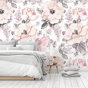 Bedroom - A bright bedroom with light wood floors and a wall covered in Decor2Go Wallpaper Mural featuring pink and white flowers. A simple bed with gray bedding and a wooden bedside table with a lamp.