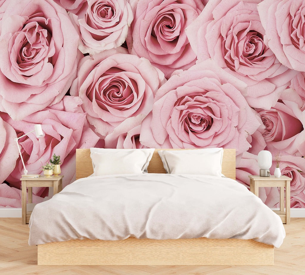 A modern bedroom with a large bed covered in white bedding, flanked by two wooden nightstands, against a vibrant feature wall decorated with Decor2Go Wallpaper Mural's Pink Paradise Wallpaper Mural featuring a close-up floral pattern of large pink roses.