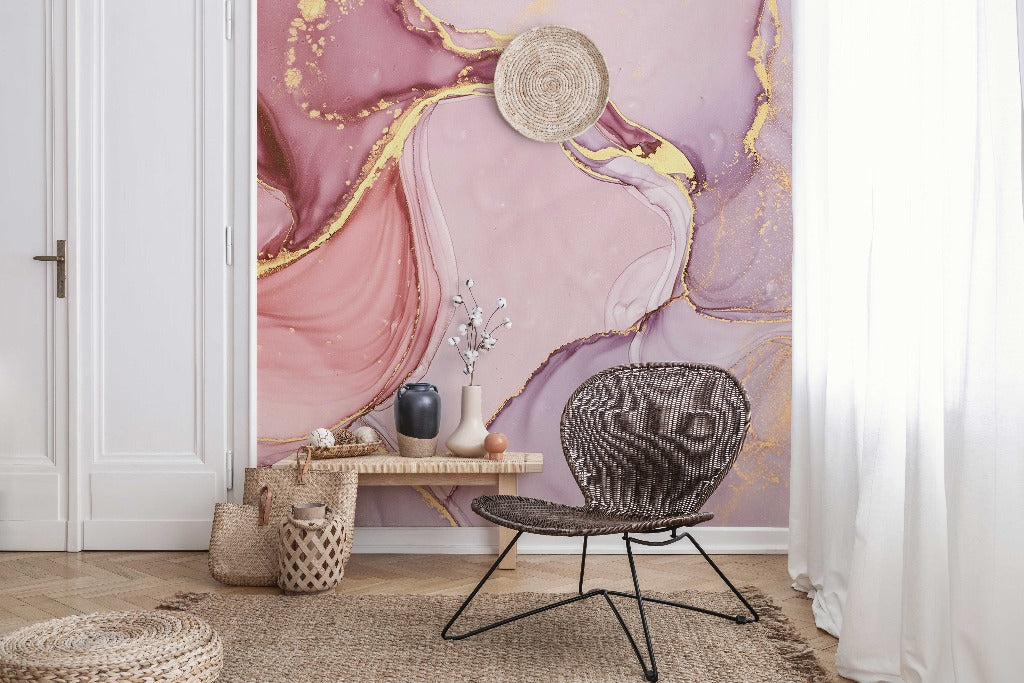 A stylish room with a large Decor2Go Pink and Gold Marble Wallpaper Mural on the wall, featuring a black wicker chair, a wooden bench with simple decor, and a straw hat hanging on the wall.