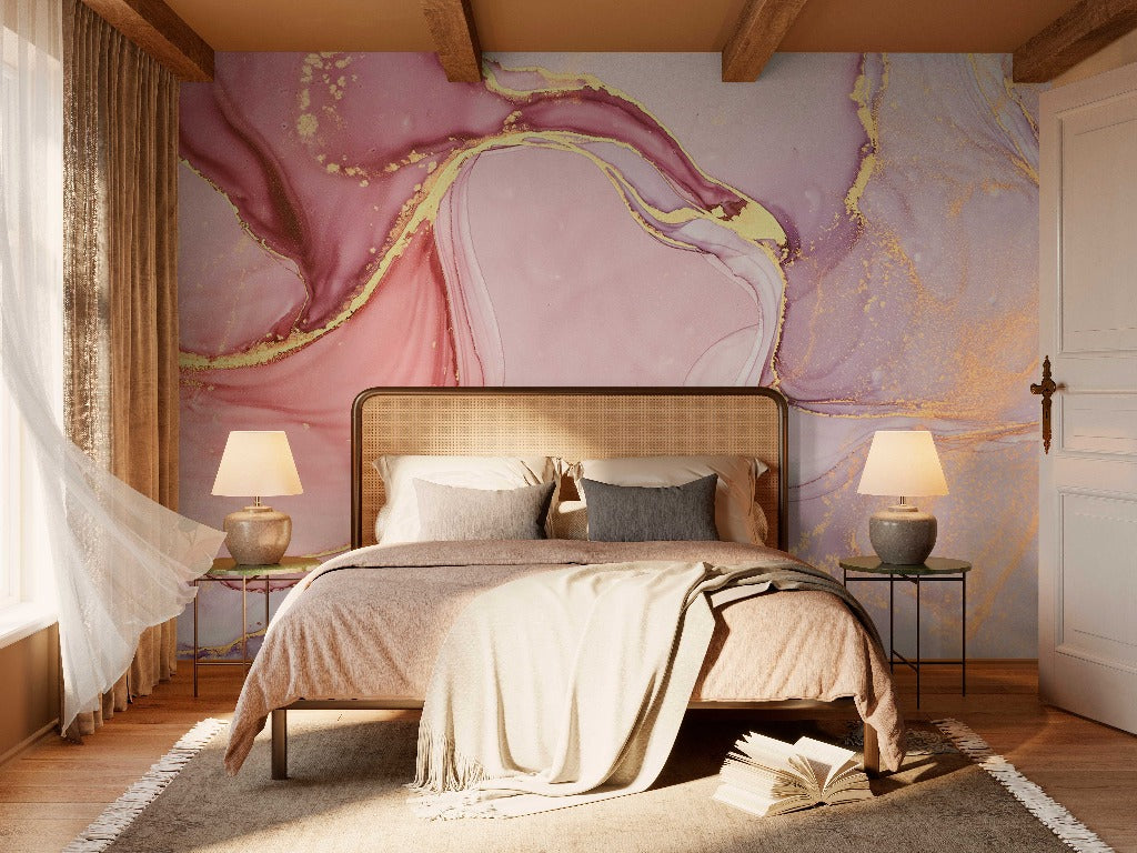 A cozy bedroom with an artistic Decor2Go Wallpaper Mural Pink and Gold Marble Wallpaper Mural above the bed, which features beige linens and earth-toned pillows. Two bedside tables with lamps flank the bed, and an open book
