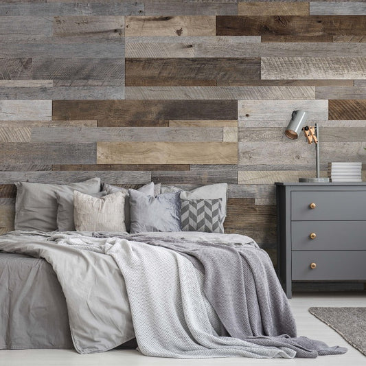 A modern bedroom featuring a large bed with gray bedding and Decor2Go Wallpaper Mural. A side table with a lamp and plants beside the bed enhances the cozy ambiance.