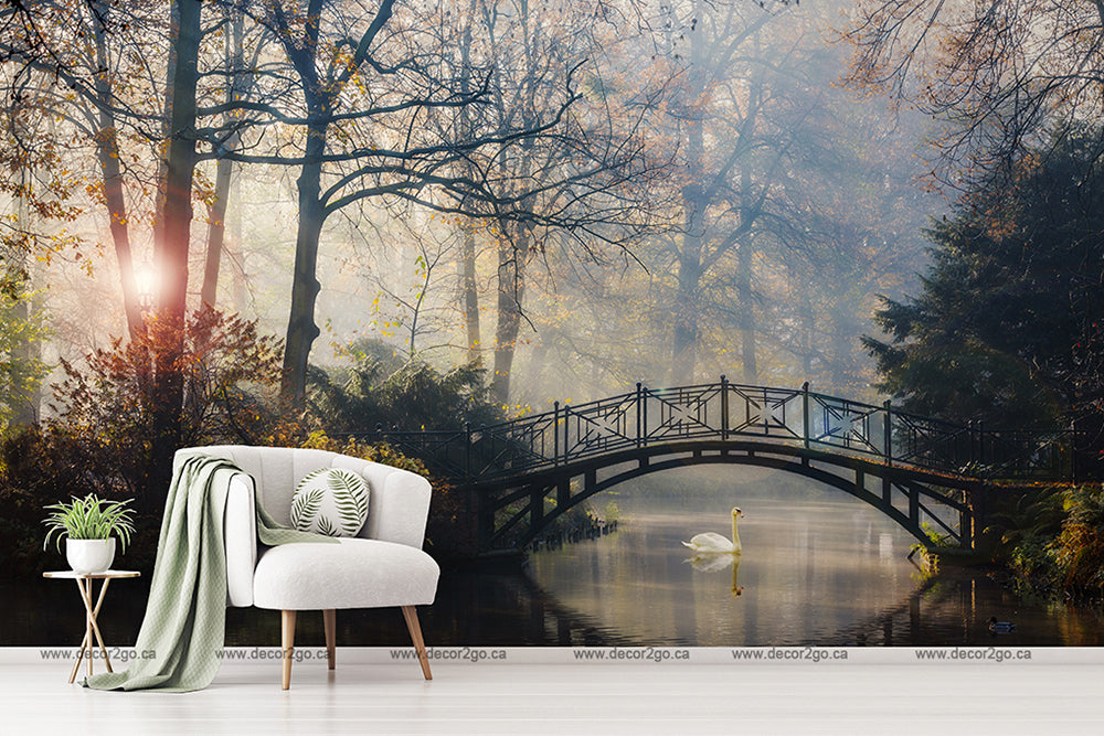 A serene living room setup with a modern white chair and a green blanket next to a small table with plants, all overlaid on Decor2Go Wallpaper Mural featuring Romantic Bridge Wallpaper Mural scene with a bridge over a misty forest.