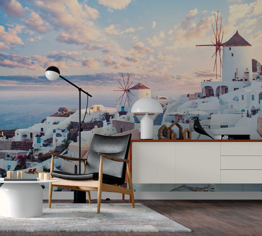 A modern living room with a stylish chair and a wall-sized Decor2Go Wallpaper Mural, displaying iconic white buildings and windmills against a vibrant sunset sky.