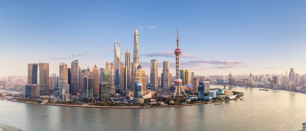 Panoramic view of the Shanghai skyline at sunset, featuring an architectural mural of the Oriental Pearl Tower and skyscrapers along the Huangpu River under a clear sky, created using Decor2Go Wallpaper Mural.
