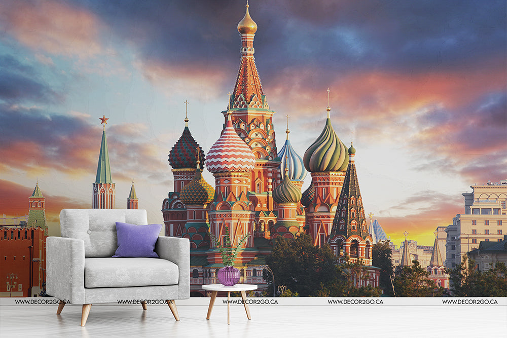 A whimsical room setup featuring a gray armchair and small round table, juxtaposed against a large custom sized Decor2Go Wallpaper Mural of St. Basil's Cathedral in Moscow under a vibrant sunset sky.