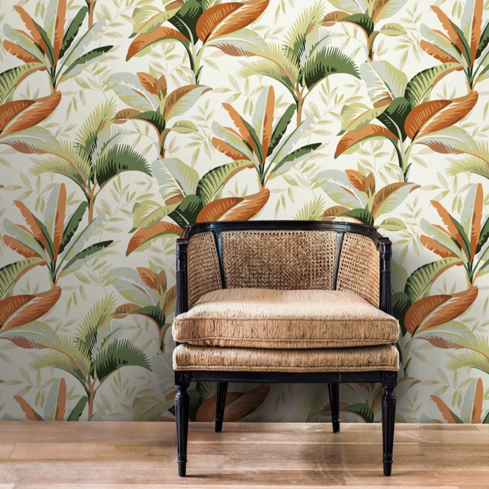 A vintage-style black wooden bench with a rattan back and a beige cushion, set against a vibrant York Wallcoverings Summerhouse Midnight Wallpaper in shades of green and orange.