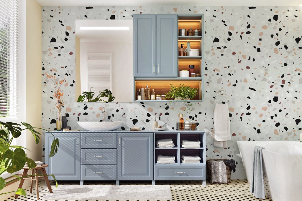 A stylish bathroom with luxurious Decor2Go Wallpaper Mural terrazzo design walls, featuring a blue vanity cabinet, wooden shelving, a freestanding bathtub, and a decorative plant. Bright natural light illuminates the space.