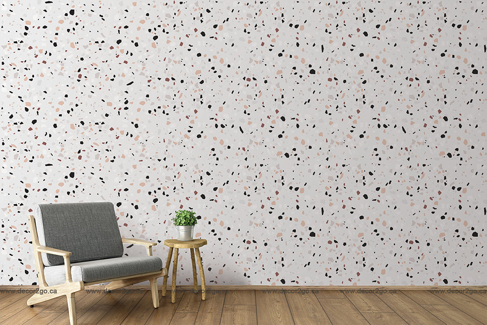 A modern room with a luxurious Decor2Go Wallpaper Mural on the wall in red, black, and beige speckles. There's a gray armchair and a wooden stool with a small green plant on it.