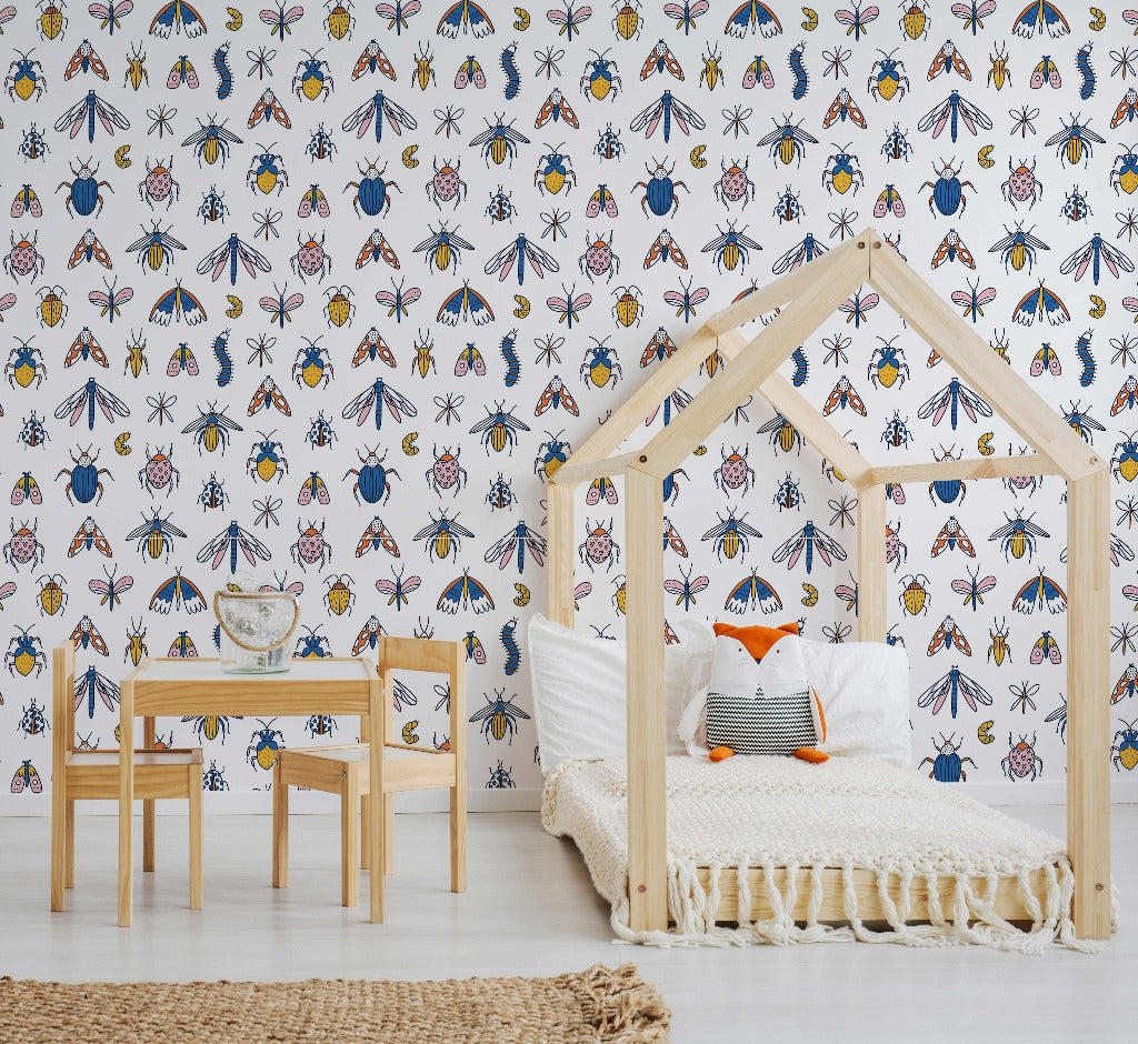 A children's room with a house-shaped bed frame, a small wooden desk and chair, and a colorful Decor2Go Wallpaper Mural. A rug and scattered cushions complete the cozy space.