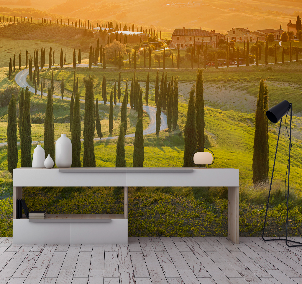 A modern living room with a white console table, featuring a lamp and vases, overlooking a large wall image of the vibrant green hills of Decor2Go Wallpaper Mural with rolling hills and a winding road