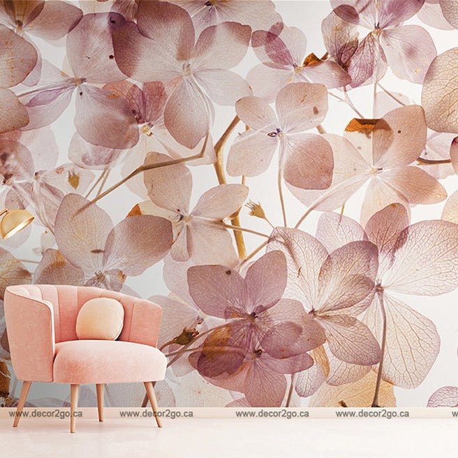 A room featuring a large Translucid Flowers Wallpaper Mural design with delicate, translucent pink hydrangea petals. In the center, a soft pink armchair sits against the floral backdrop, exemplifying feminine decor from Decor2Go Wallpaper Mural.