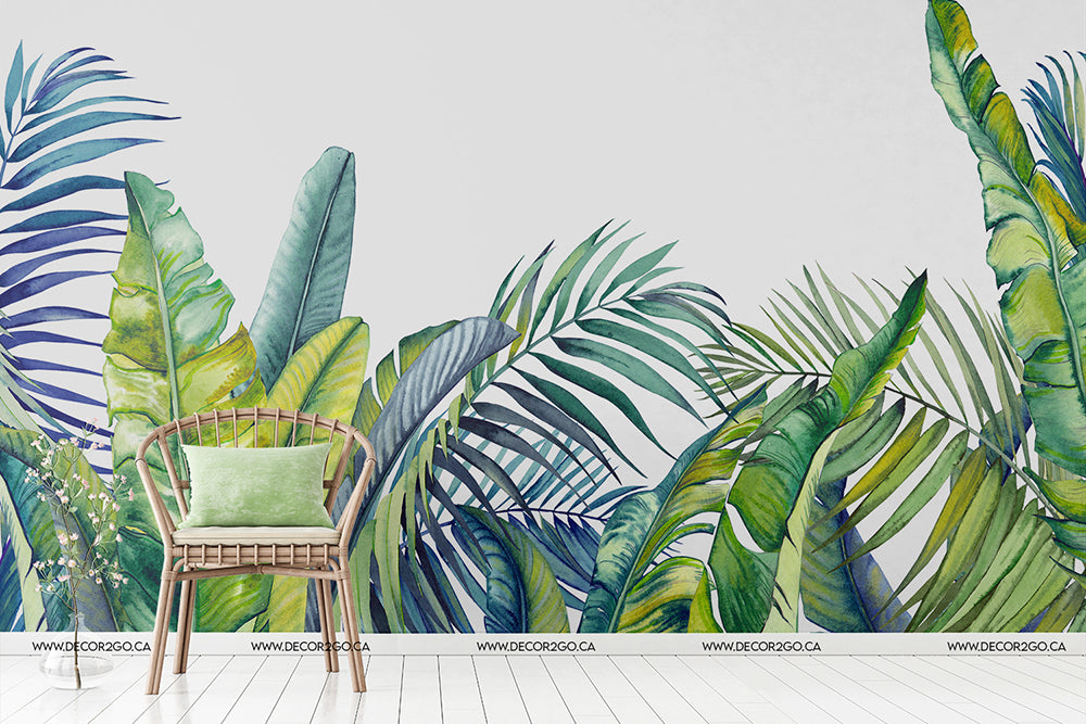 A serene indoor setting featuring a single wicker chair with a green cushion against a backdrop of vibrant and artistically painted palm tree leaves mural, evoking a calm and natural ambiance created by Decor2Go Wallpaper Mural's Tropical Blue Tropical Bloom Wallpaper Mural.