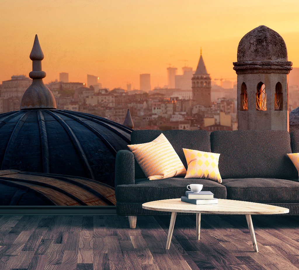 A stylish interior with a comfy sofa adorned with cushions, a small coffee table, and a panoramic view of a cityscape at sunrise through a window with dome architecture inspired by Decor2Go Wallpaper Mural's Turkish Sunrise Wallpaper Mural.
