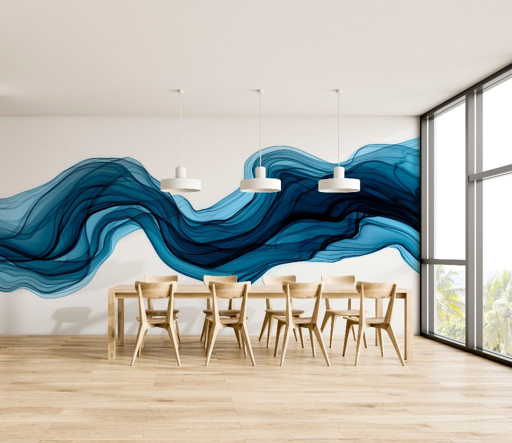 A minimalist dining room with a large Decor2Go Wallpaper Mural depicting an abstract blue wave on the feature wall, wooden chairs around a rectangular table, pendant lights, and a window with a view of greenery.