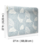 Image showing a roll of York Wallcoverings Vinca Glint Wallpaper Metallic (60 Sq.Ft.) with a blue and white leaf pattern. The wallpaper, made from durable non-woven material, is displayed partially unrolled. Dimensions are indicated: 27 feet (8.23 meters) long by 27 inches (68.58 centimeters) wide.