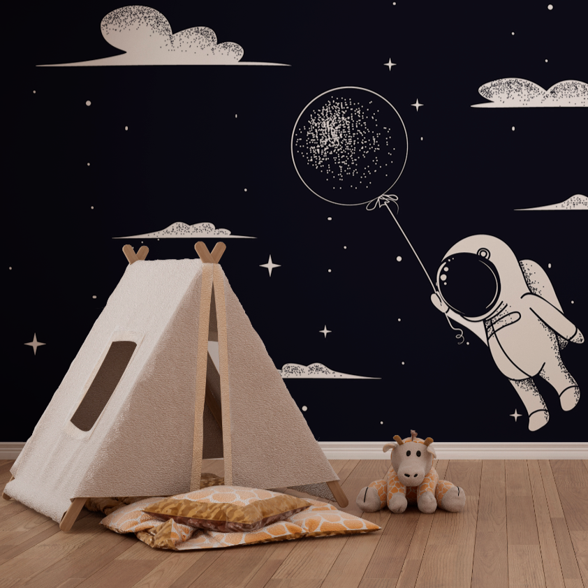 A cozy children's playroom designed for space fanatics. The wall features a Decor2Go Wallpaper Mural of a dark blue sky with stars, clouds, and an astronaut holding a glittering balloon.