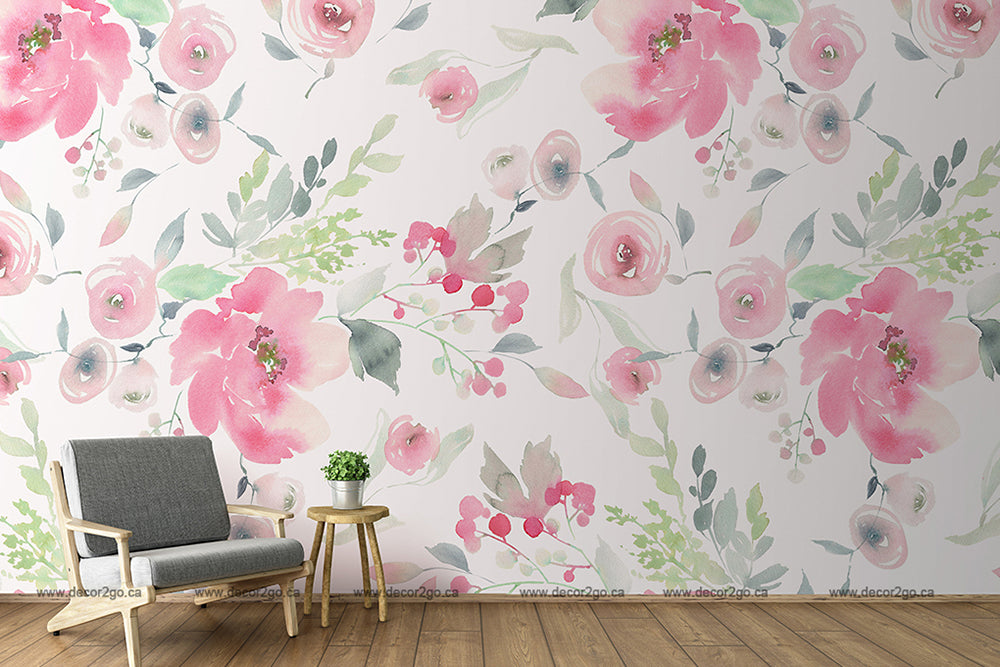 A stylish room with a feminine room decor, featuring the Decor2Go Watercolor Pink Flowers Wallpaper Mural with large pink flowers and green leaves. A modern grey chair and small wooden table with a potted plant are near the wall.