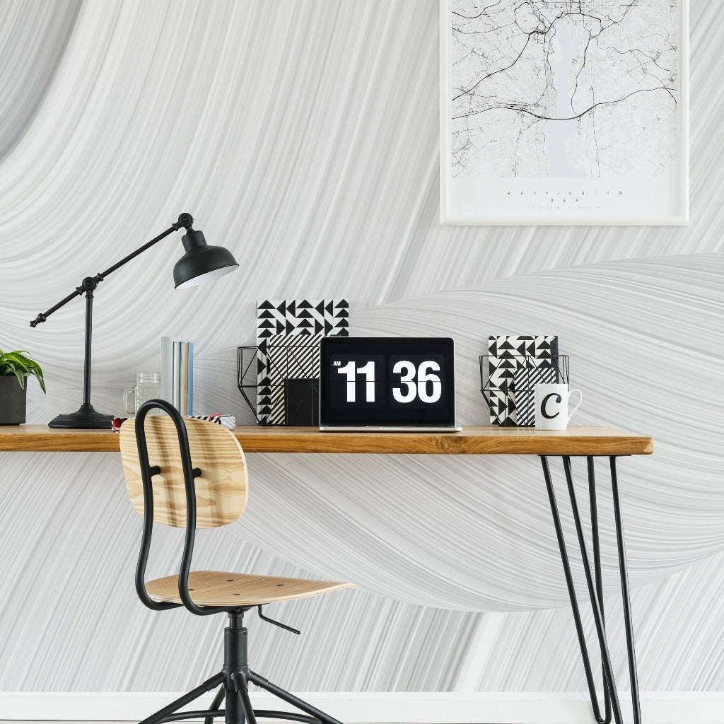 A modern home office desk with a digital clock, lamp, framed map, decorative books, a plant, and a mug. A minimalist chair sits under the desk against Decor2Go Wallpaper Mural.