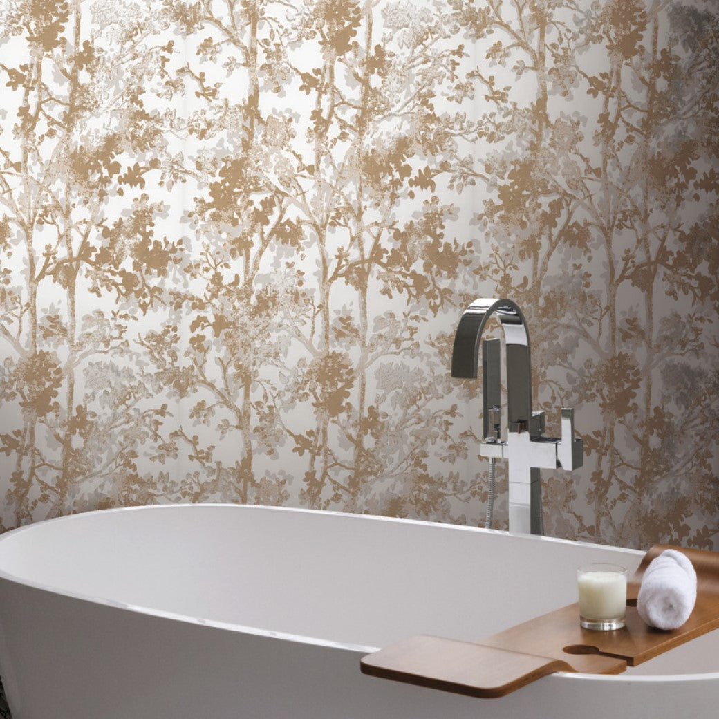 A modern bathroom has a white freestanding tub with a chrome faucet and a wooden bath tray holding a candle and rolled towel. The White & Gold Shimmering Foliage Wallpaper by York Wallcoverings adds an elegant touch to the space.