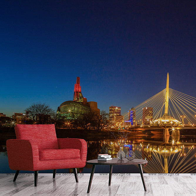 A red armchair and a small table with books are positioned against a backdrop of the Decor2Go Wallpaper Mural Winnipeg Bridge Wallpaper Mural, depicting a romantic atmosphere in a picturesque urban setting.