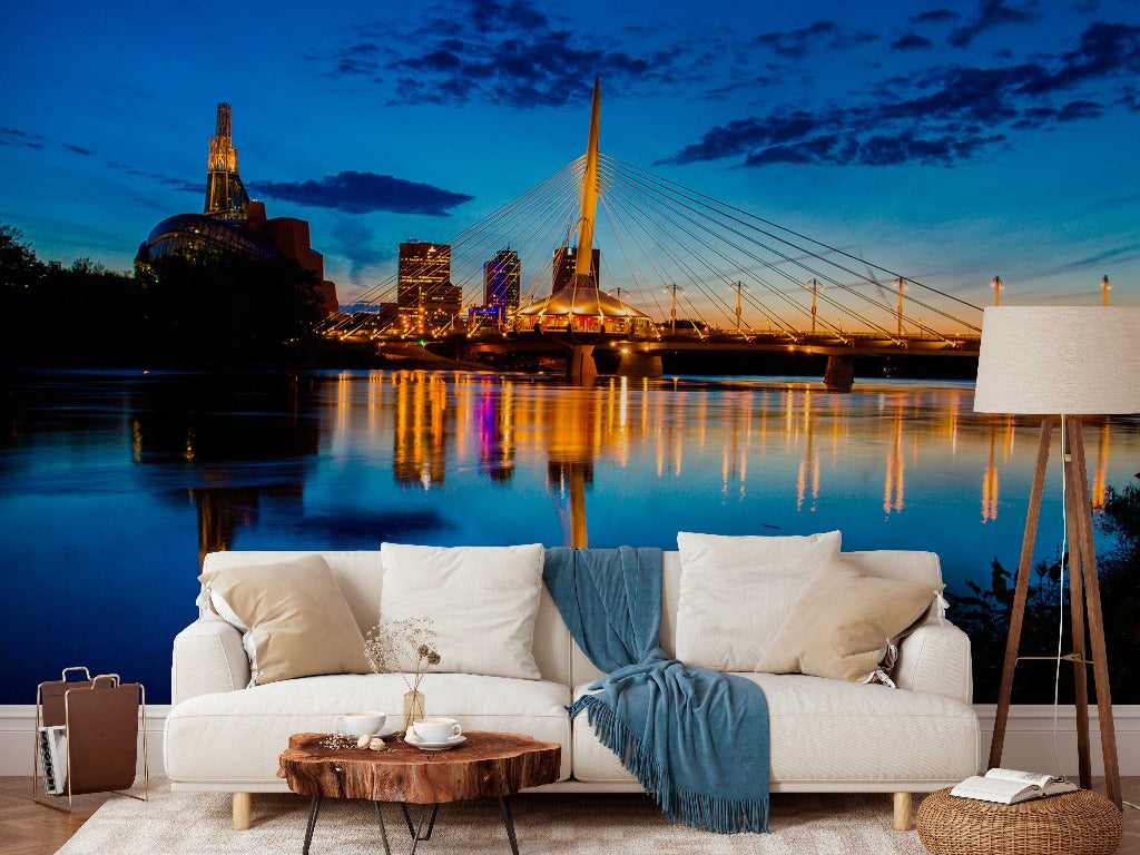 Modern living room with a large window showcasing a scenic cityscape mural of Decor2Go Wallpaper Mural and a suspension bridge at dusk, reflected on a tranquil river.