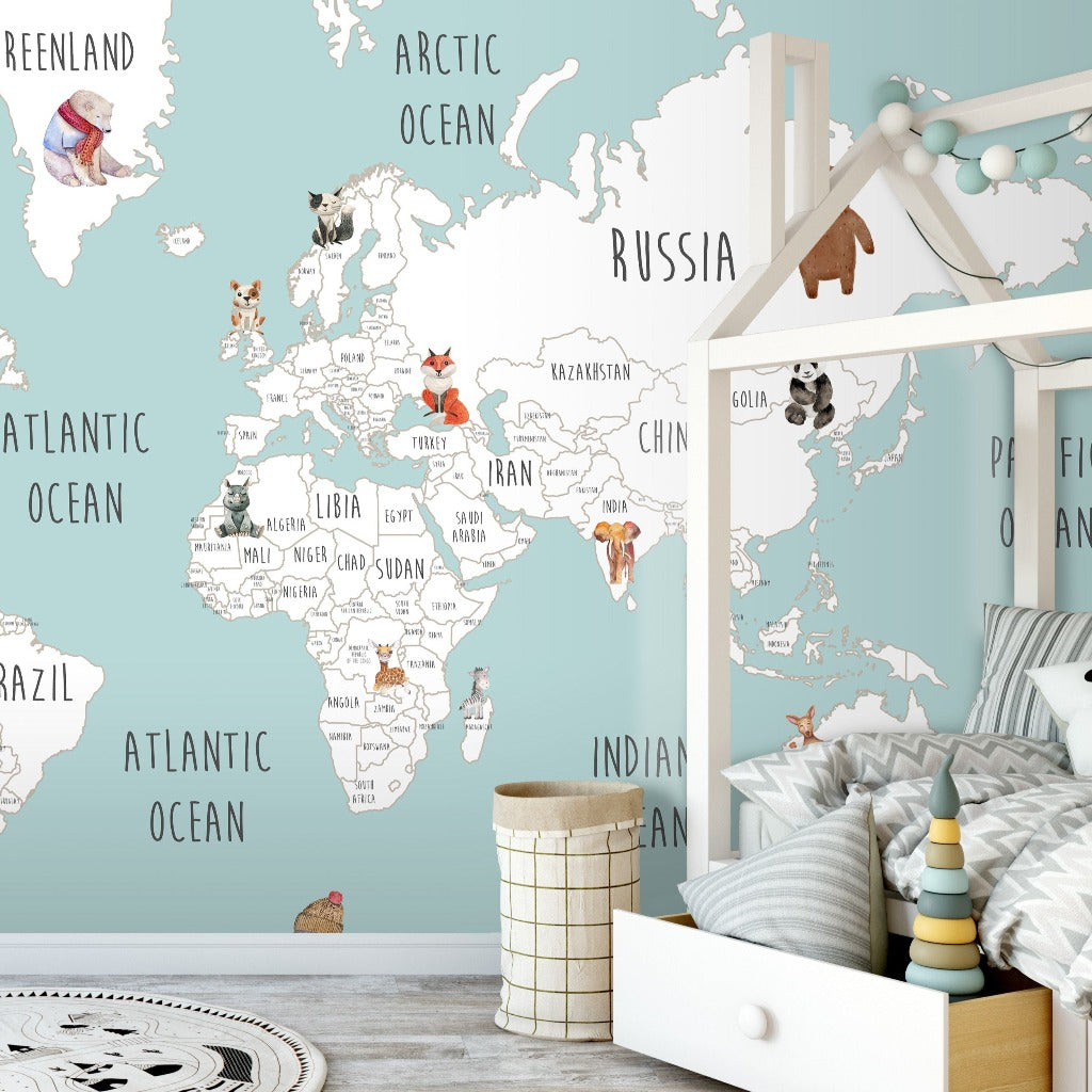 A colorful educational Decor2Go Wallpaper Mural depicting a World Map with Wild Animals covers the wall of a children's bedroom, featuring a white bed with patterned bedding and a play area with toys.
