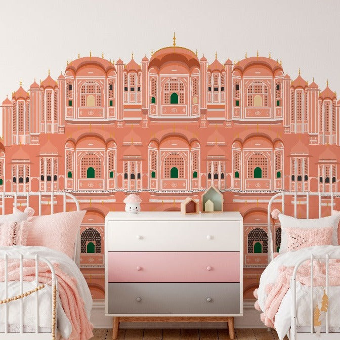 A children's bedroom with twin beds, both with pink bedding. The room features a large wall mural depicting a grand, ornate palace inspired by Jaipur Mahal, beautifully illustrated in red and pink from Decor2Go Wallpaper Mural.