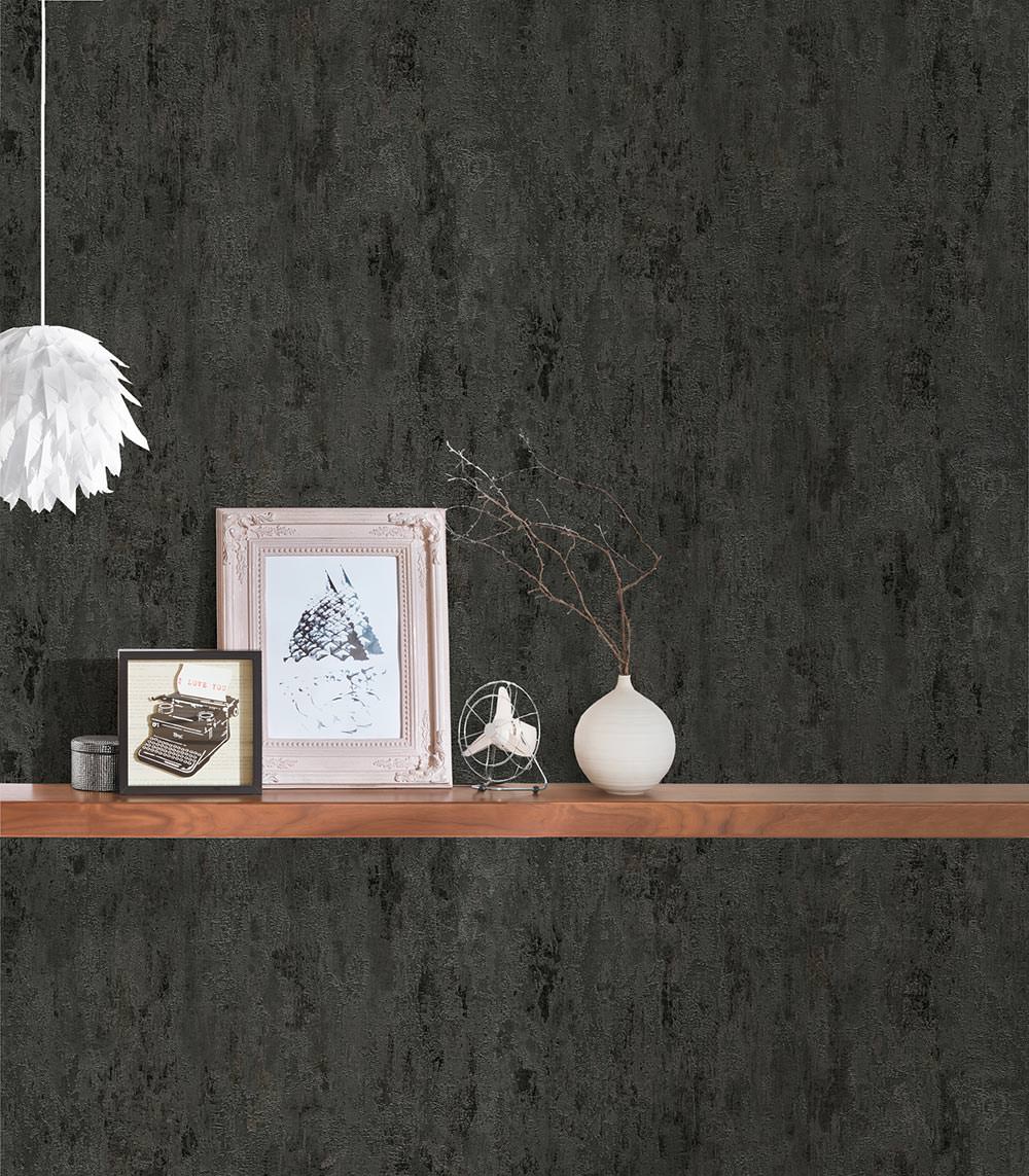 A decorative shelf against a dark textured Ontario Decoro Texture Wallpaper (56 SqFt) displays a white framed picture, a small framed illustration of a typewriter, a white vase with branches, a silver wire sculpture, and two small cylindrical containers. A white pendant light with a feather-like design hangs above.