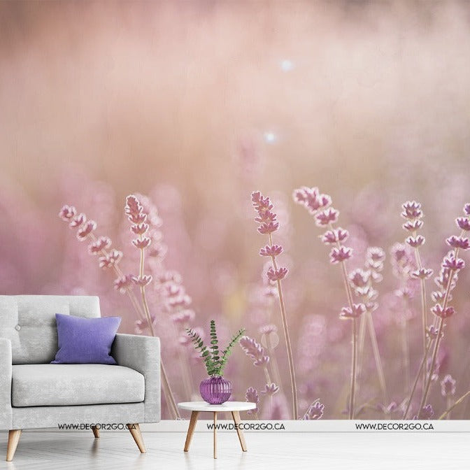 An artistic rendering of a soft grey armchair with a purple pillow, next to a small table with a potted plant, set against Decor2Go Wallpaper Mural's Field of Dreams Wallpaper Mural background of purple wildflowers.