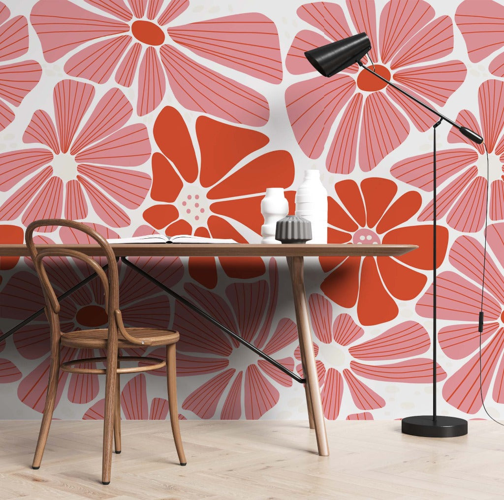 A stylish workspace featuring a desk with a bentwood chair, set against a Groovy Flowers Wallpaper Mural in shades of red, pink, and white with Daisy patterns. A modern black floor lamp arch.