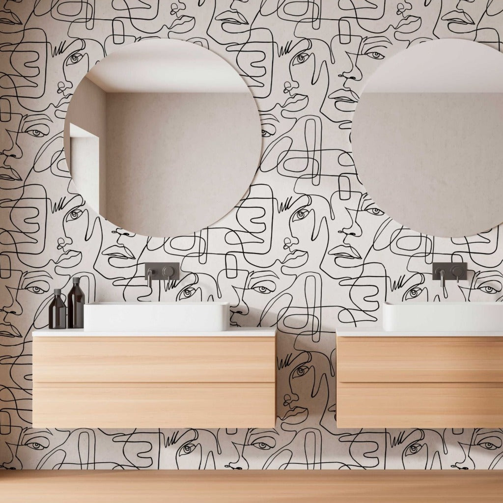 Modern bathroom interior with twin sinks and mirrors against a feature wall decorated with Decor2Go Wallpaper Mural of abstract faces. Light wood cabinetry adds warmth to the design.