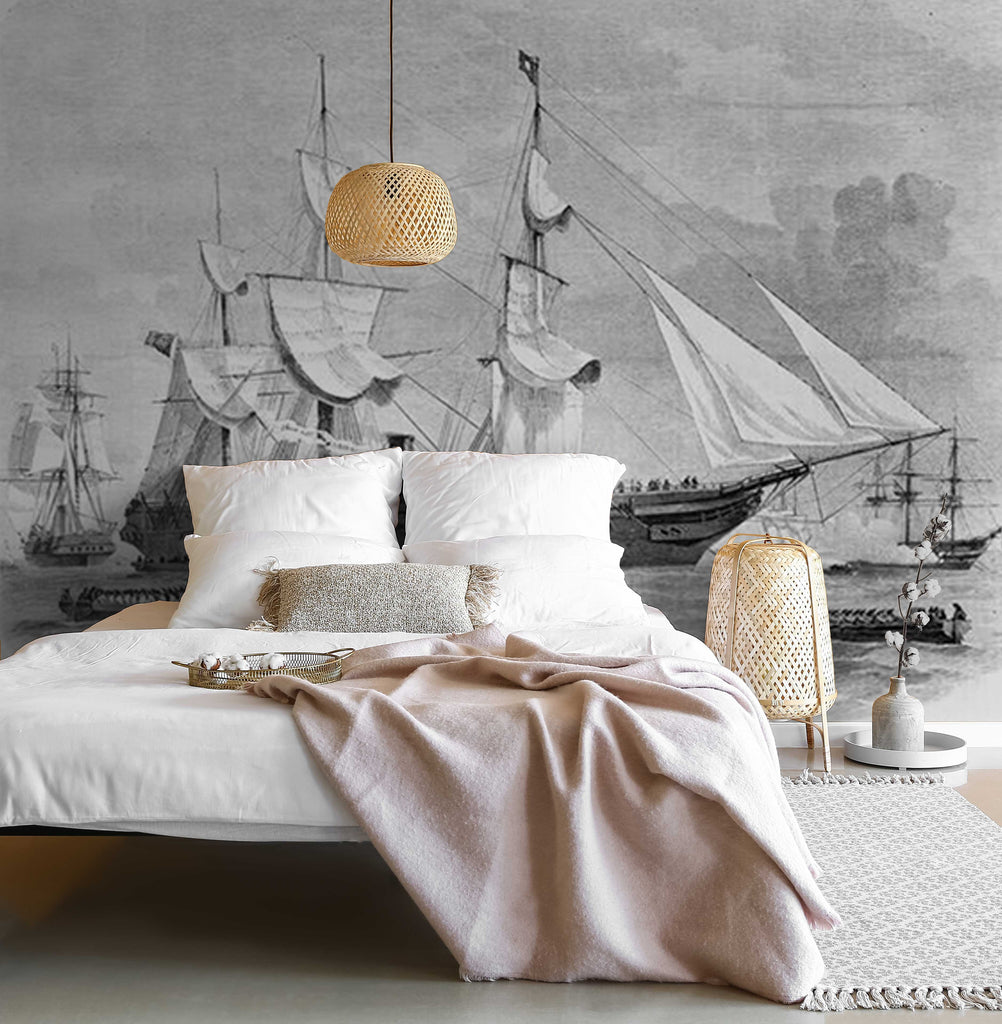 A modern bedroom with a maritime theme inspired by pirate stories, featuring a large wall mural of vintage ships, a white bed with plush linens, and pendant lighting, complemented by natural textures and soft Decor2Go Wallpaper Mural Sailing Away Wallpaper Mural.