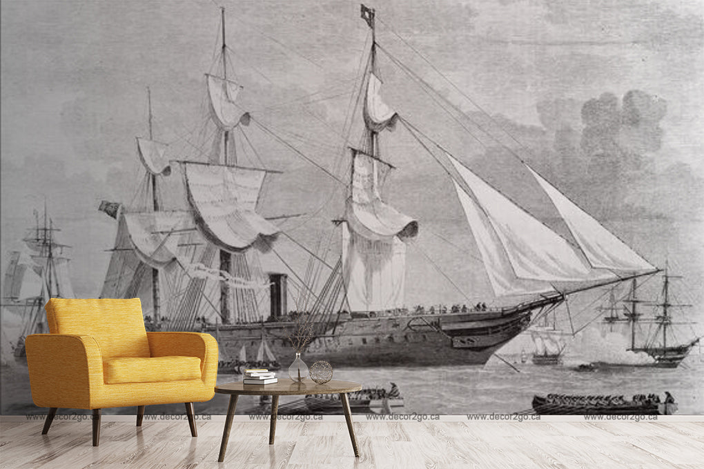 A mural of historical ships on a gray wall beside a modern, bright yellow armchair with a small round coffee table hosting books and a cup. The scene combines old maritime art with contemporary furnishings, reflecting Decor2Go Wallpaper Mural's Sailing Away Wallpaper Mural.