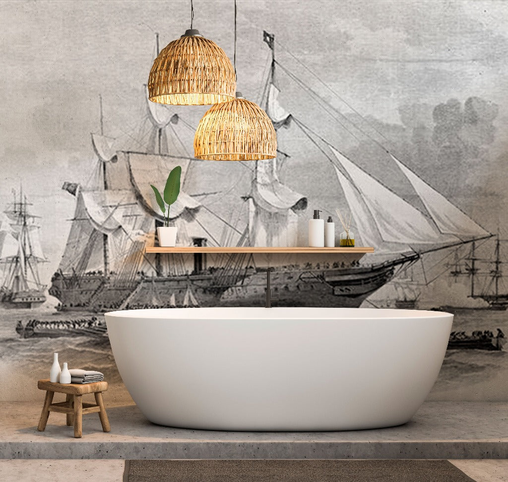 A minimalist bathroom featuring a white freestanding bathtub, a wooden stool with towels and bottles, and two wicker pendant lights. The backdrop is the Decor2Go Wallpaper Mural's Sailing Away Wallpaper Mural of an old sailing ship in grayscale, adding serene seascape vibes to the nautical-themed modern space.