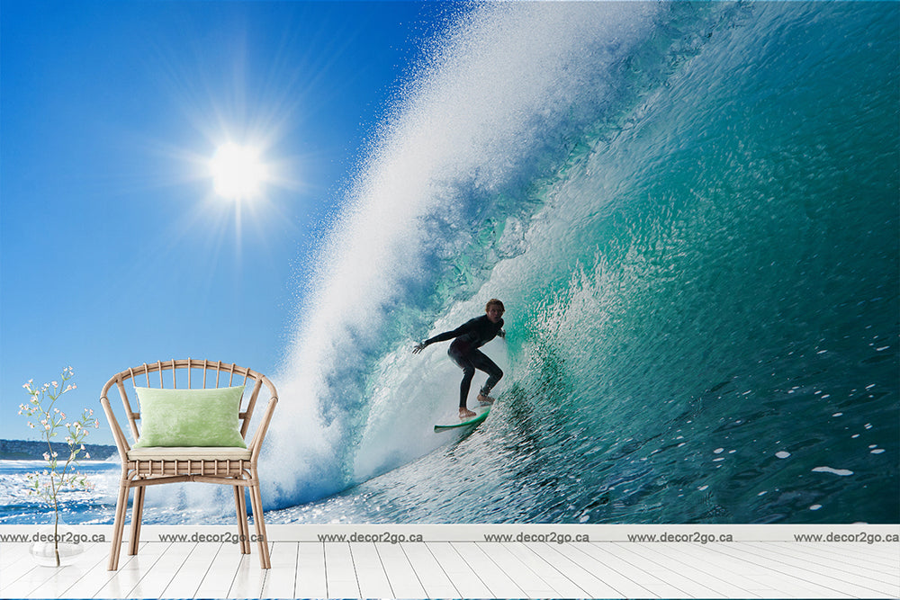 A surfer rides a clear blue wave perfectly, juxtaposed against a surreal interior decor with a stylish chair and a wooden floor under a sunny sky, transforming the space into a Decor2Go Wallpaper Mural Surfer on a Wave.