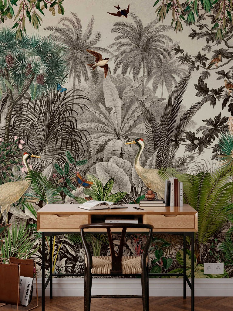 A stylish workspace with a vintage-style wooden desk and black metal legs, featuring an open book and decorative items, set against a Vintage Jungle Wallpaper Mural by Decor2Go Wallpaper Mural with lush plants and birds.