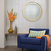 Living Room - A contemporary corner showcases a blue armchair embellished with a geometric-patterned pillow and an orange throw. In the backdrop, tall yellow and metallic vases are set against a wall adorned with York Wallcoverings' Split Levels Wallpaper (60 SqFt). The space is further enhanced by a round mirror, adding the perfect modern decor flair