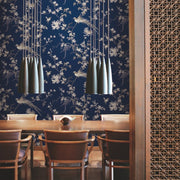 Dining Room - The exudes elegance with a long wooden table and chairs. Modern pendant lights with a metallic finish hang above the table, while the walls are adorned with York Wallcoverings' Blue Bird And Blossom Chinoserie Wallpaper. A beautifully carved wooden partition adds a touch of sophistication on the right