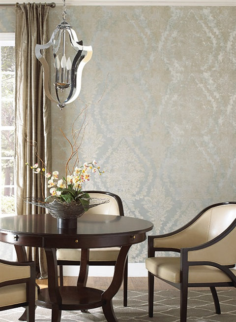 Dining Room - A cozy area with a dark round table, four cream-colored cushioned chairs, and a metallic chandelier above. A potted orchid with branches sits on the table. York Wallcoverings Classic Charleston Damask Wallpaper in Blue (60 SqFt) and a window with tan curtains complete the elegant setting